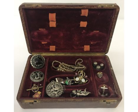 A vintage leather manicure box containing a quantity of vintage costume jewellery. To include a Miracle brooch, faux pearls a