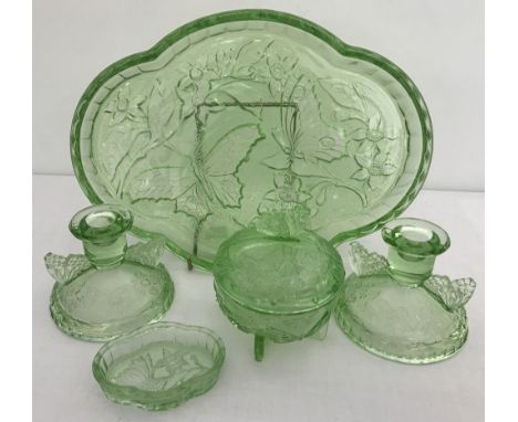 An Art Deco green glass ladies dressing table set with butterfly detail. Comprising: a pair of candlesticks, lidded trinket p