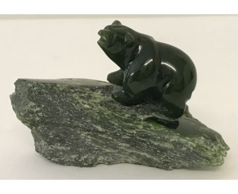 A carved Nephrite jade bear standing on natural jade platform.