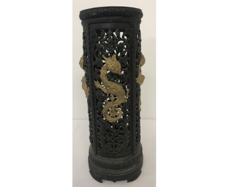 A vintage circular cast iron black and gold stick stand with oriental dragon design.