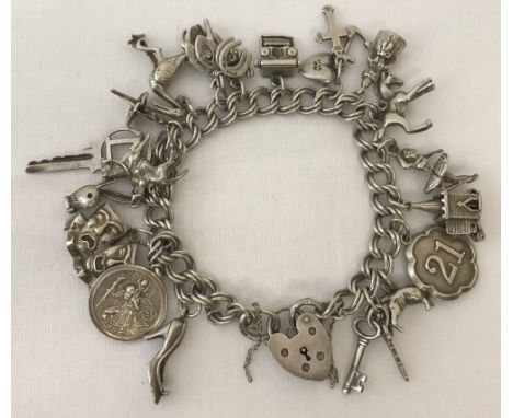  A vintage silver double link charm bracelet, with padlock and safety chain &amp; holding 18 charms. Charms include a church 