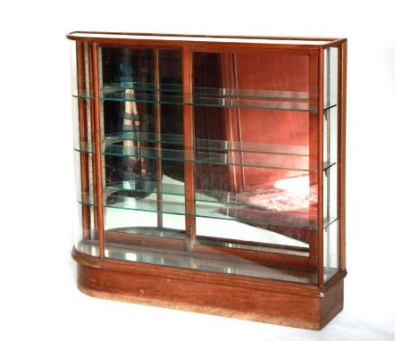 An early 20th century walnut shop display cabinet with curved glass panel set to one end and sliding mirrored doors with shel