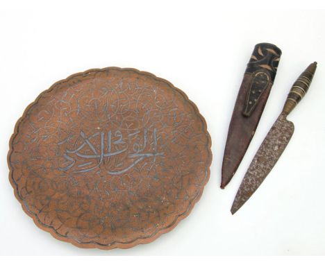 An Islamic copper tray with silver overlay decoration, 27cms diameter; together with a Middle Eastern knife in leather scabba