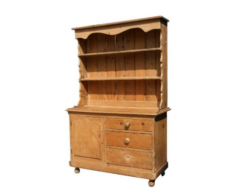 A pine dresser with two-tier plate rack above a cupboard with three drawers and single panel door, on bun feet, 126cms wide.C