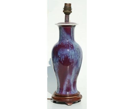 A Chinese sang de boeuf style baluster vase converted to a table lamp, on a wooden base, 29cms high.