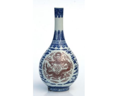 A Chinese underglaze blue, white and copper red bottle vase decorated with dragons amongst clouds, blue seal mark to the unde