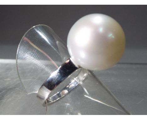 An 18 ct white gold ring, stamped 750, set with large cultured pearl (approximately 14 mm diameter), size O. This lot must be