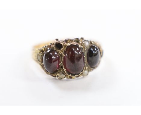 A Victorian 15ct gold, foil backed three stone cabochon garnet and seed pearl cluster set half hoop ring, size O, gross weigh