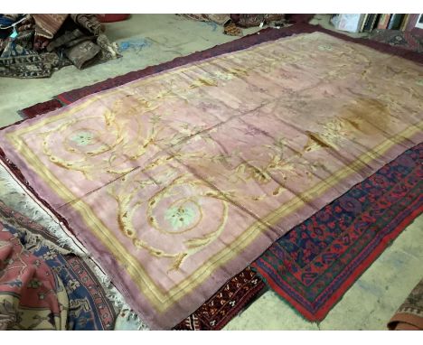 An antique Donegal carpet, with scrolling motifs on a pale, pink ground, cut and reduced in size, 386 x 210cm