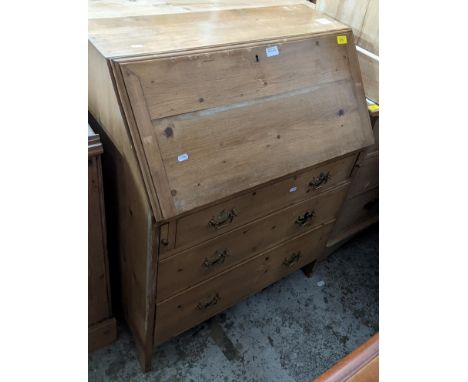 A 20th century pine bureau with fall flap revealing a pigeonhole interior, over one short and two graduated long drawers on s