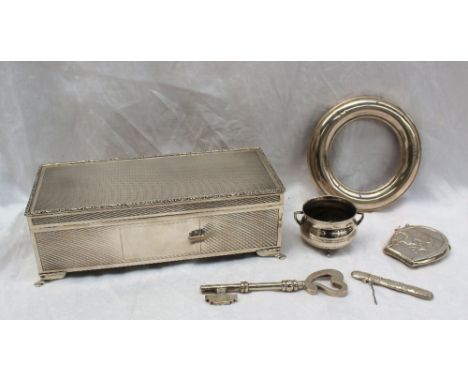 An Elizabeth II silver cigarette box of rectangular form with a leaf cast border and engine turned decoration on four splayed