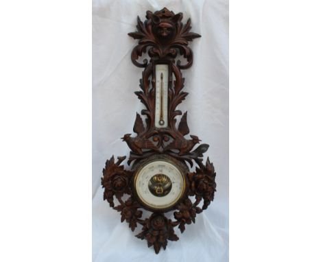 A 19th century Black Forest carved oak barometer carved with a fox mask and birds with a mercury thermometer, with an insight