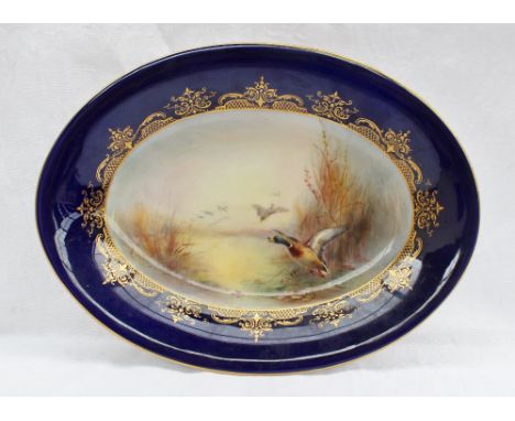 A Royal Worcester porcelain oval dish painted with a mallard and other ducks in flight from a pond signed for James Stinton t