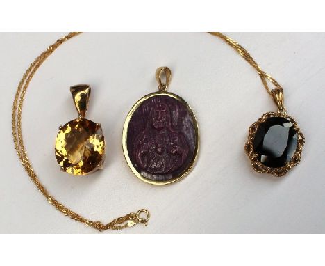 A 9ct yellow gold mounted ruby cameo pendant together with a citrine and white topaz pendant and another pendant