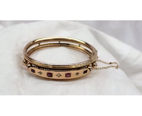 A yellow metal hinged bangle set with three rubies and three diamonds, approximately 15 grams CONDITION REPORT: One ruby miss