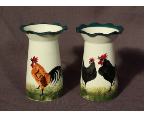 A pair of Wemyss ware pottery flared vases decorated with a black cockerel and hen to the one and a brown cockerel and a hen 