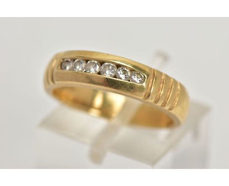A YELLOW METAL DIAMOND RING, wide band measuring approximately 4.7mm, designed with a row of channel set, slightly graduated 