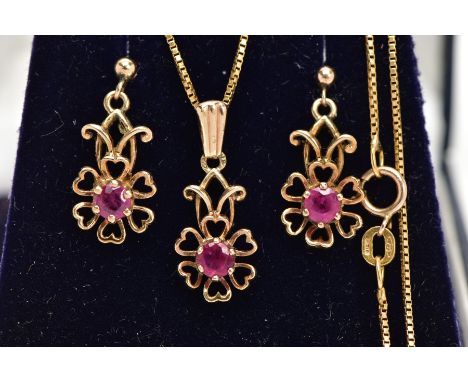 A MATCHING PENDANT NECKLACE AND EARRING SET, the pendant designed as an openwork flower, set with a circular cut ruby in a si