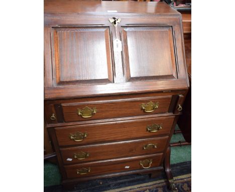 A 20th century oak bureau, of narrow proportions, panel fall front enclosing a tooled and gilt writing surface and a fitted i