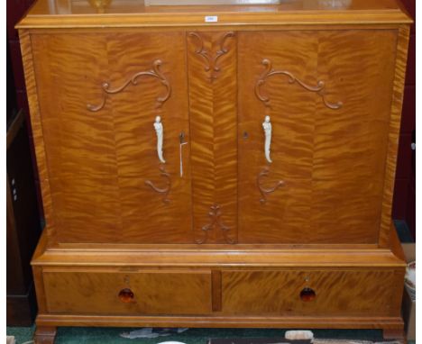 A 20th century satinwood and pine side cabinet, moulded rectangular top above a pair of cupboard doors carved and applied wit