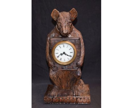 A 20th century Black Forest style bear clock, carved as seated, holding the clock dial to his chest, mechanical manual wind m