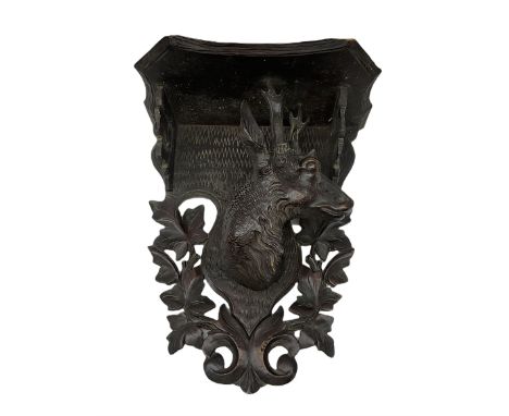 Carved Black Forrest style wooden wall bracket, with shaped shelf supported by a shaped back carved with the head of a deer a