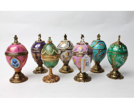 Seven House of Faberge musical eggs and lidded egg trinket pot on raised metal stand