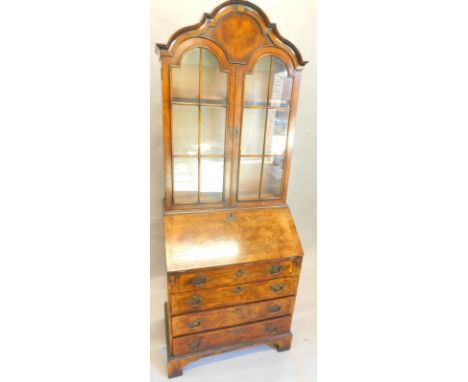 A walnut bureau bookcase in mid 18thC style, the top with an arched moulded crest above two glazed doors, enclosing adjustabl