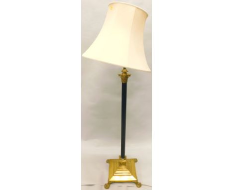 A brass and bronzed standard lamp, with a cream fabric shade and a Corinthian column, on a stepped square base with paw feet,