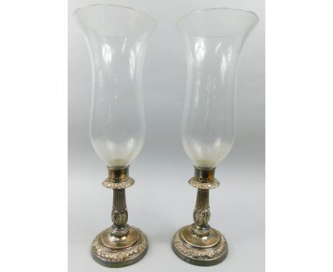 A pair of Sheffield plate type storm lanterns, each with a clear glass shade, bases decorated with leaves etc., 44cm high.