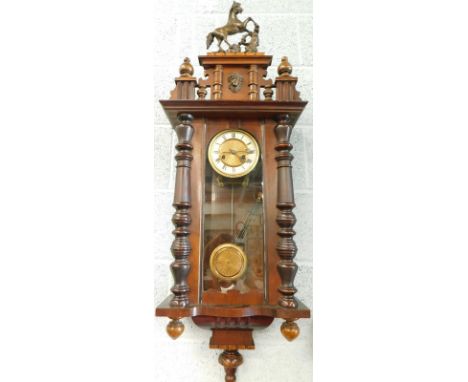 A Black Forest type wall clock, with composition rearing horse crest, enamel type dial with Roman numerals in a walnut case, 
