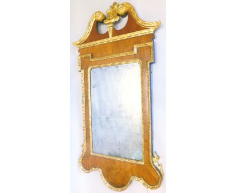 An 18thC walnut wall mirror, with a parcel gilt swan neck pediment, centered by a cartouche, the frame with egg and dart moul