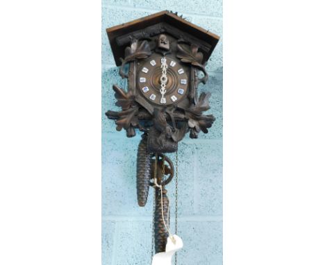An early to mid 20thC Black Forest cuckoo clock, mounted with a stag crest, the case decorated with oak leaves and a dead bir