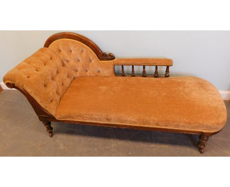 A Victorian walnut chaise longue, with a part show-frame upholstered in brown buttoned dralon, on turned tapering legs with c