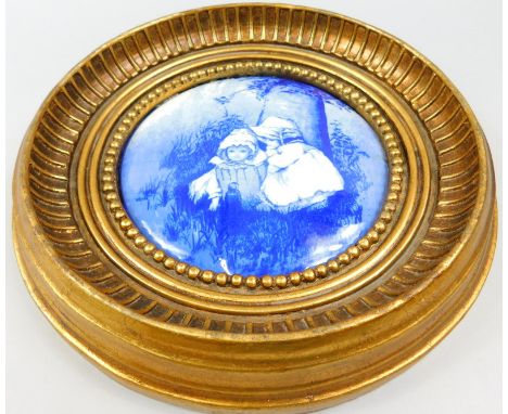 A blue and white porcelain plaque, decorated with children within a gilt frame, Royal Doulton stamp, 27cm dia