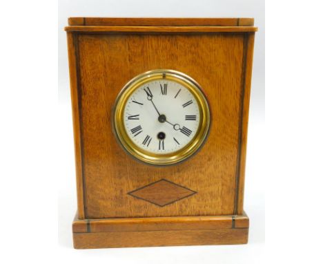 An Arts and Crafts style oak mantel clock, inlaid with lozenges, the enamel dial with Roman Numerals, 27cm high.
