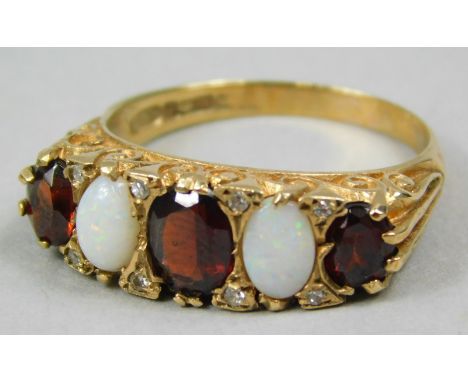 A 9ct gold dress ring, set with five oval cut stones, set with three garnet and two opals, with scroll design sides, 5.8g all