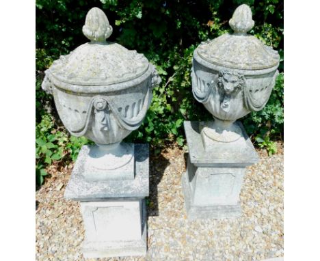A pair of composition gate finials or urns, each in neo classical style, decorated with lion masks, swags etc., on rectangula