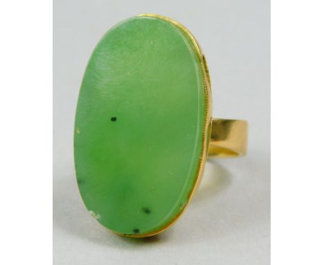 A jade set dress ring, with central oval jade, in a pierced setting (AF), yellow metal, unmarked, 8.9g all in. 