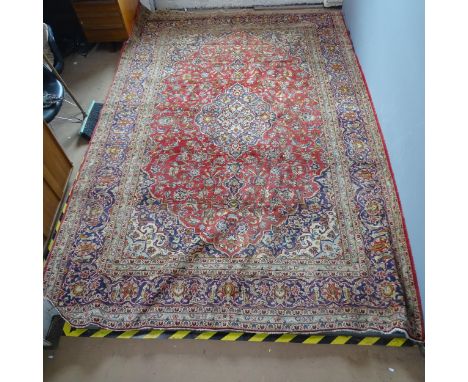 A red-ground Persian Keshan carpet. 376x247cm.Loss to edges, no fringe, faded and worn. Piece missing from one side. 
