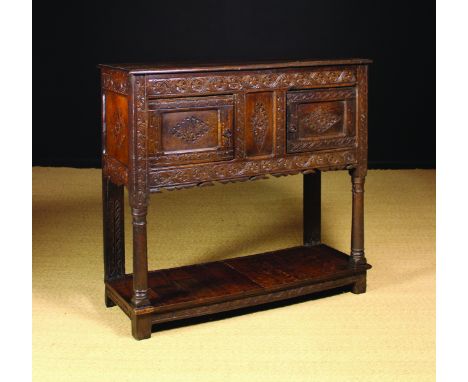 A Late 17th Century Carved Oak Livery Cupboard having two lozenge carved doors flanking a centre panel between rails of folia