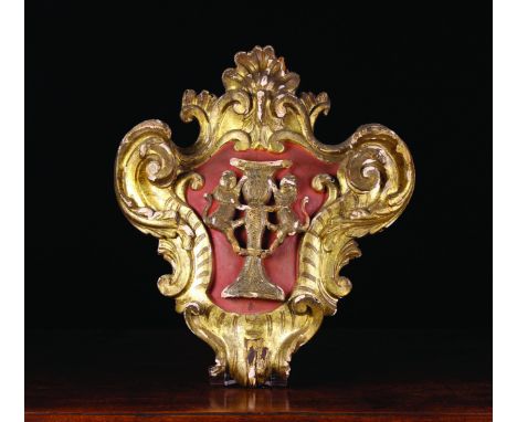 An 18th Century Carved Giltwood Armorial Cartouche emblazoned with a pair of rampant lions flanking an urn in a painted centr