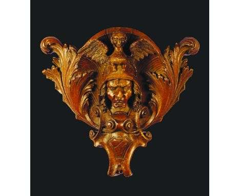 An 18th Century Oak Wall Bracket carved on the form of a man's head rising from a scrolled cartouche and wearing a helmet sur