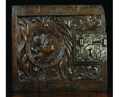 An Early 16th Century Oak Panel Door carved with a portrait roundel amidst scrolls of zoomorphic foliage with face mask termi