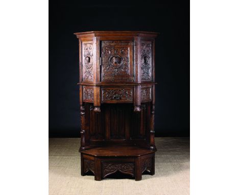 A 19th Century French Renaissance Style Oak Dressoir. The canted cupboard carved in relief with protuberant heads encircled b