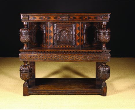 A 17th Century Carved Oak Court Cupboard. The upper section having a moulded top with marquetried frieze raised on bulbous cu