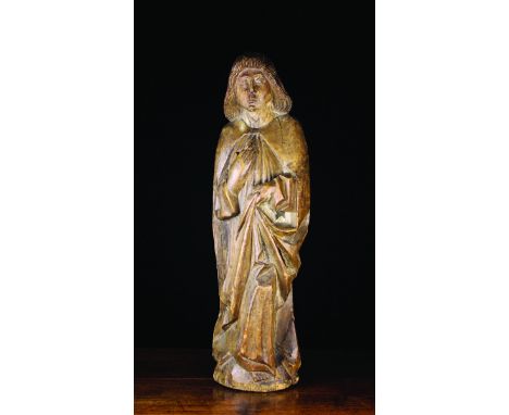 A 14th Century Style Carving of Saint John depicted as a young man with shoulder length hair wearing a long cloak draped in d