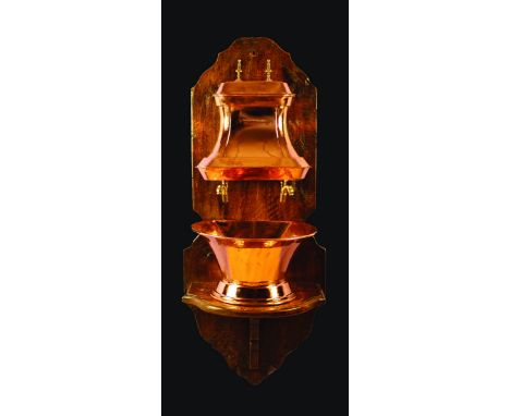A Copper Water Fountain having a lidded cistern with twin brass dolphin head spouts above a flared basin on pedestal foot, mo