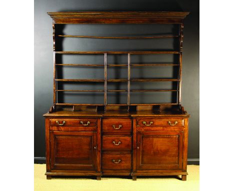 A Late Georgian Oak Break-front Dresser with Rack. The rack having a moulded cornice above two open shelves with plate groove