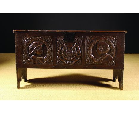 A 17th Century Boarded Oak Coffer. The front board carved with three panels; portrait heads in laurel wreaths flanking a Tudo